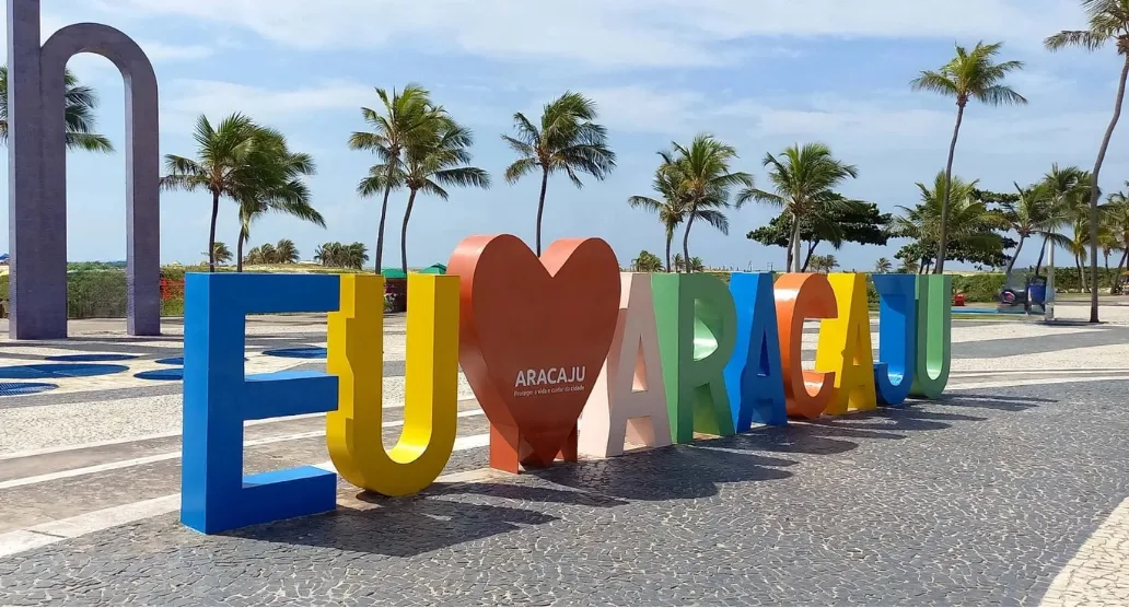 Quiosques de palha na beira da praia, com coqueiros atrás